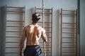 Fit young man in gym standing topless , holding a climbing rope. Rear view. Royalty Free Stock Photo