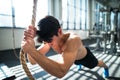 Fit young man in gym working out with climbing rope. Royalty Free Stock Photo