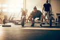 Fit young man lifting weights with others in a gym Royalty Free Stock Photo