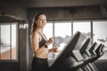 Fit young woman caucasian running on machine treadmill workout in gym. Glad smiling girl is enjoy with her training process. Royalty Free Stock Photo