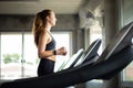 Fit young woman caucasian running on machine treadmill workout in gym. Glad smiling girl is enjoy with her training process. Royalty Free Stock Photo