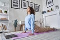 Fit young woman doing yoga stretching exercise watching online class on laptop. Royalty Free Stock Photo