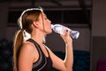 Fitness young woman drinking water in the gym. Muscular woman taking break after exercise Royalty Free Stock Photo