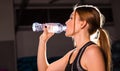 Fitness young woman drinking water in the gym. Muscular woman taking break after exercise Royalty Free Stock Photo