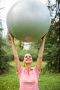 Fit young woman exercising, holding fitness ball high above her head Royalty Free Stock Photo