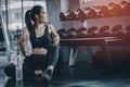 Fit young woman sitting and resting after workout or exercise in fitness gym. woman at gym taking a break and relax Royalty Free Stock Photo