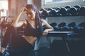 Fit young woman sitting and resting after workout or exercise in fitness gym. woman at gym taking a break and relax with water in Royalty Free Stock Photo