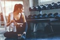 Fit young woman sitting and resting after workout or exercise in fitness gym. woman at gym taking a break and relax with water in Royalty Free Stock Photo