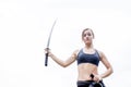 Fit young woman in sports bra holding katana in hawk wing position and looking at camera