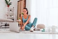 Fit young woman watching sports video on laptop, getting ready for online training at home