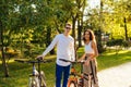 Fit, youthful and smiling couple is looking at the camera, cycling in the city park, laughing and spending their leisure on a