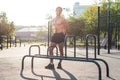 Fitnes man posing on street fitness station showing his muscular body Full lenght portrait.