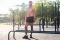 Fitnes man posing on street fitness station showing his muscular body Full lenght portrait.