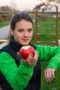 Fitnes trainer offering an apple at outdoor gym.