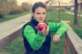 Fitnes trainer offering an apple at outdoor gym.