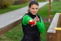 Fitnes trainer offering an apple at outdoor gym.
