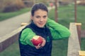 Fitnes trainer offering an apple at outdoor gym.