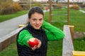 Fitnes trainer offering an apple at outdoor gym.