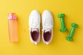Fitness accessories concept. Top view photo of white sneakers pink bottle of water and green dumbbells on isolated yellow Royalty Free Stock Photo