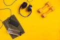 Fitness accessories on a yellow background. Dumbbells, bottle of water, towel and headphones. Royalty Free Stock Photo