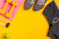 Fitness accessories on a yellow background. Sneakers, bottle of water, apple and dumbbells. Royalty Free Stock Photo