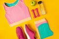 Fitness accessories on yellow background. Sneakers, bottle of water, dumbbells and sport top. Royalty Free Stock Photo