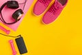 Fitness accessories on a yellow background. Sneakers, bottle of water, earphones and dumbbells. Royalty Free Stock Photo