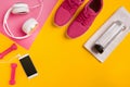 Fitness accessories on a yellow background. Sneakers, bottle of water, earphones and dumbbells. Royalty Free Stock Photo