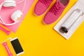 Fitness accessories on a yellow background. Sneakers, bottle of water, earphones and dumbbells. Royalty Free Stock Photo