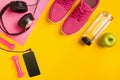 Fitness accessories on yellow background. Sneakers, bottle of water, headphones and smart. Royalty Free Stock Photo