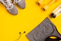 Fitness accessories on a yellow background. Sneakers, bottle of water, headphones and sport top. Royalty Free Stock Photo