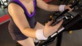 Fitness application, obese girl riding exercise bike and scrolling mobile gadget