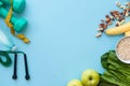 Fitness background with bottle of water, apple, dumbbells, nuts, and tape measure on blue table. Royalty Free Stock Photo