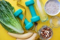 Fitness background with bottle of water, apple, dumbbells, nuts, and tape measure on yellow background. Royalty Free Stock Photo