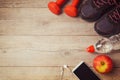 Fitness background with bottle of water, dumbbells and athletic shoes. View from above