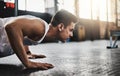 Fitness belongs to the focused. a young man doing pushups in a gym. Royalty Free Stock Photo