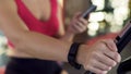 Fitness bracelet on womans hand, athletic girl riding exercise bike, closeup