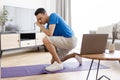 Fitness burnout. Exhausted arab man tired of online workout exercising at laptop sitting on fitness floor at home