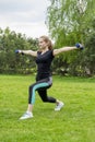 Fitness classes. A girl stands in a warm-up pose of the hands in different directions in the hands of a dumbbell