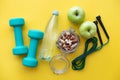 Fitness concept - apples, water, nuts, dumbbells and skipping rope on yellow background. Royalty Free Stock Photo