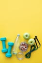 Fitness concept - apples, water, nuts, dumbbells and skipping rope on yellow background. Copy space. Royalty Free Stock Photo