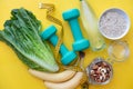 Fitness concept with bottle of water, apple, dumbbells, nuts, and tape measure on yellow background. Royalty Free Stock Photo