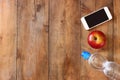 Fitness concept with bottle of water, mobile phone and apple over wooden background. filtered image Royalty Free Stock Photo