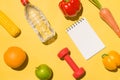 Fitness concept. Collection of fresh fruits with dumbells and water bottle on yellow background Royalty Free Stock Photo