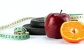 Fitness concept, dumbbell with red apple, half orange and measuring tape