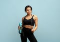 Fitness concept. Fit african american woman with jump rope and bottle of water posing over blue background Royalty Free Stock Photo