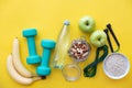 Fitness concept - fruits, water, nuts, dumbbells and skipping rope on yellow background. Royalty Free Stock Photo