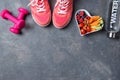 Fitness concept, pink sneakers, dumbbells, bottle of water and plate with vegetables and berries on a beton background, top view,