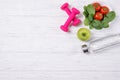 Fitness concept, spinach with tomatoes, bottle with water, green apple and pink dumbbells, diet, top view Royalty Free Stock Photo