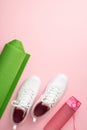 Fitness concept. Top view vertical photo of white sports footwear exercise mat and pink bottle of water on isolated pastel pink Royalty Free Stock Photo